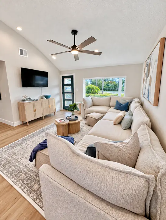 Living room with a large sectional, ceiling fan and a big window to the garden